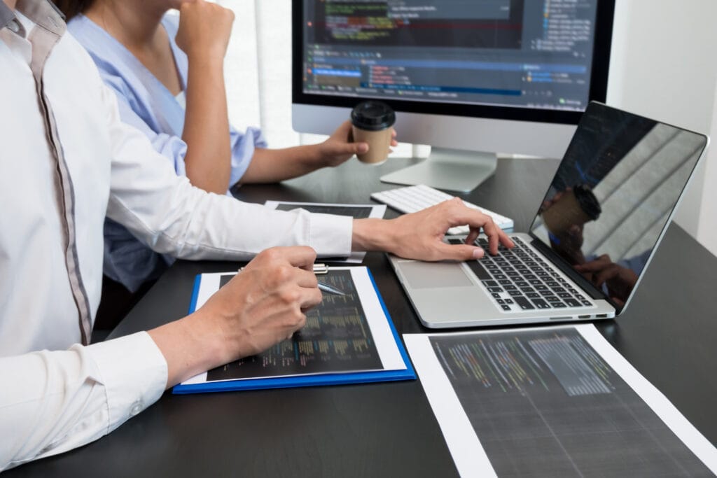 Team of programmers working with computer programming, professional development, and coding technology for an artificial intelligence project.