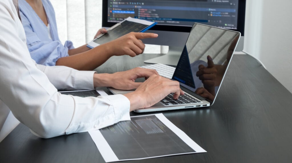 Team of programmers working with computer programming, professional development, and coding technology for an artificial intelligence project.