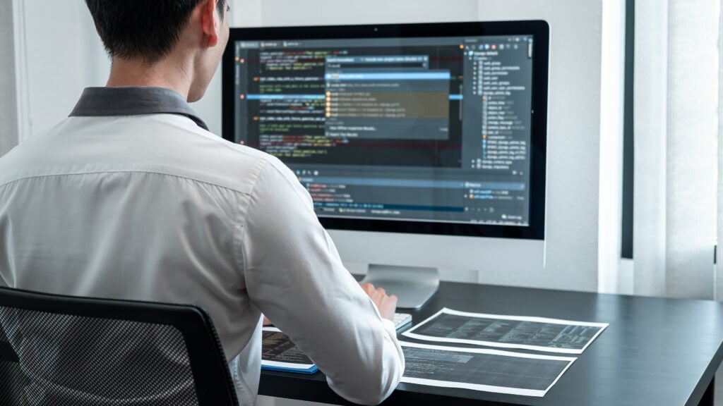 Professional programmer working on a project in data science on the desktop computer.